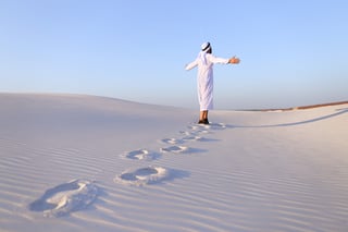 Confident Arabian Tourist Guy Walks On Foot Along Expanses Of White Sand Desert Leaving Traces
