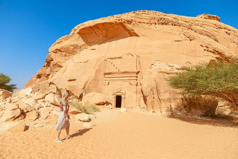 Blonde Tourist Walking In The Desert Next To Of Jabal Albanat And Giant Rock Cut Tomb 