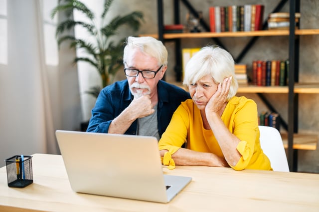 Elderly couple looking confused with laptop