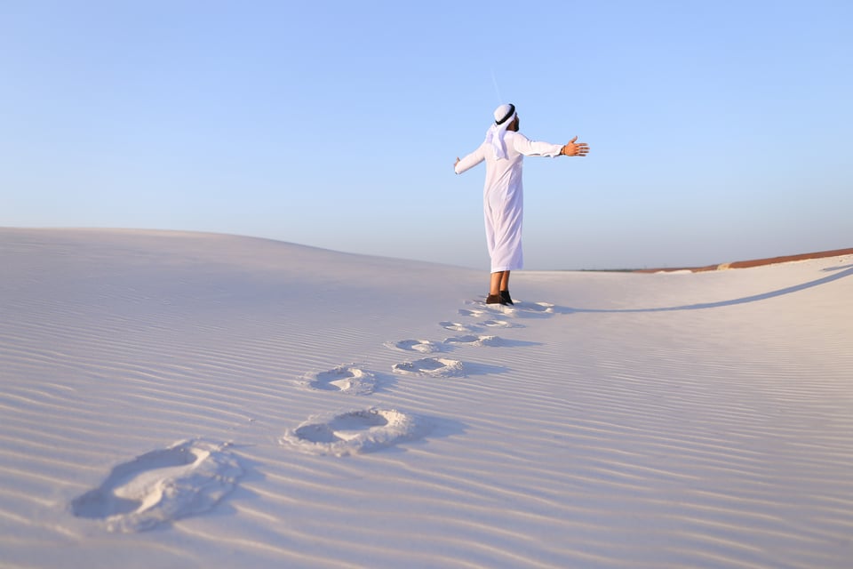 Selbstbewusster arabischer Tourist läuft zu Fuß durch die Weiten der weißen Sandwüste und hinterlässt Spuren
