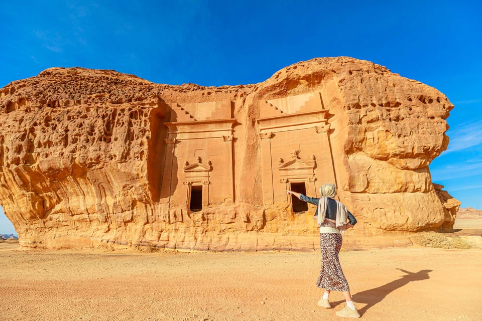 Tourist zeigt auf antike nabatäische Felsengräber von Jabal Al Ahmar im archäologischen Museum Hegra